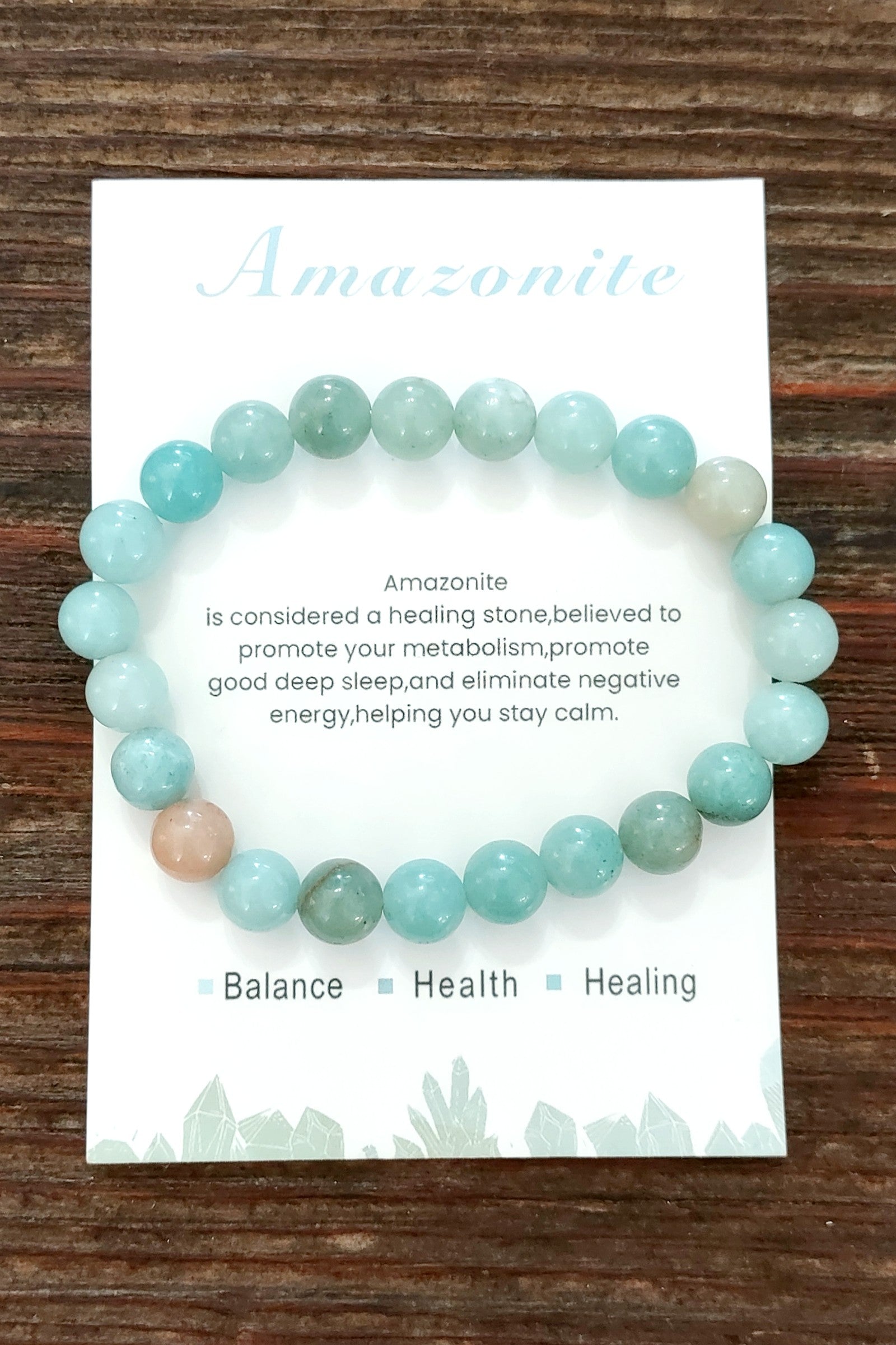 Amazonite bracelet on a card with text about its properties, displayed on a wooden surface.