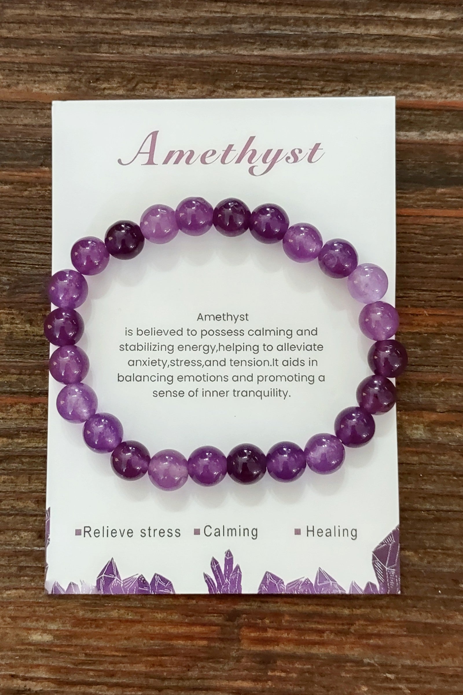 Amethyst bracelet on a card with descriptive text on a wooden surface