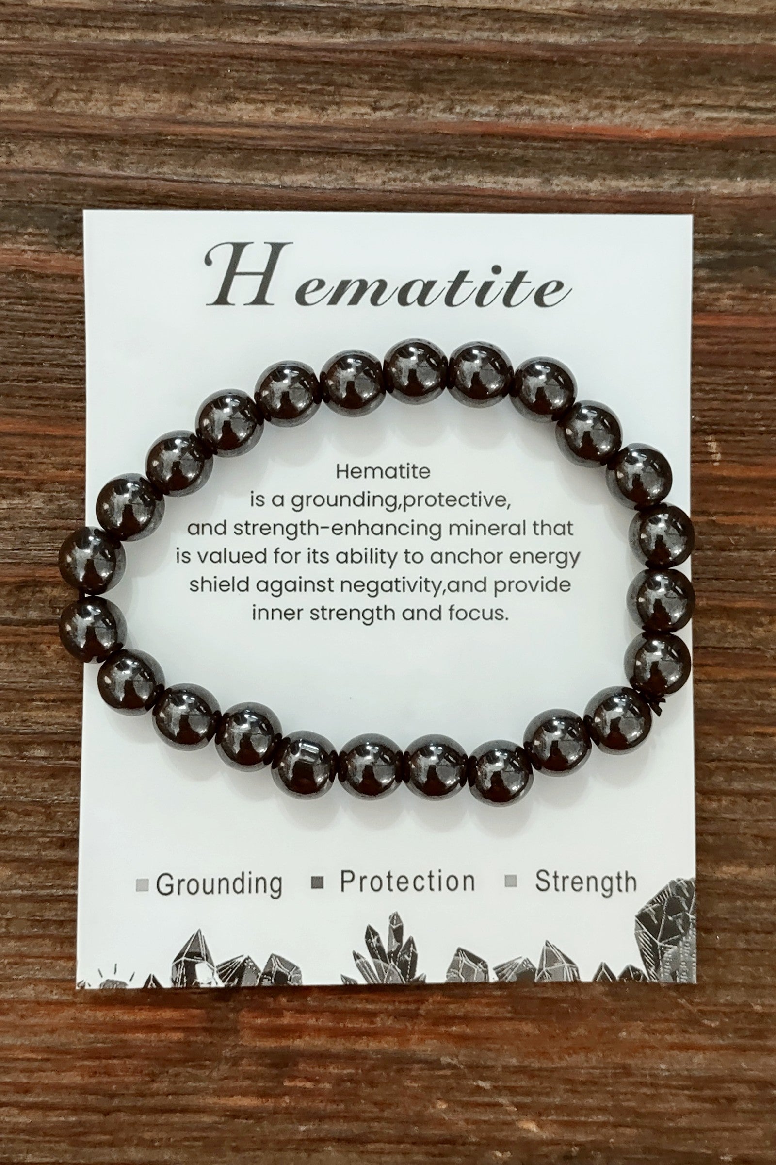 Hematite bracelet on a card with descriptive text on a wooden surface
