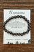 Hematite bracelet on a card with descriptive text on a wooden surface