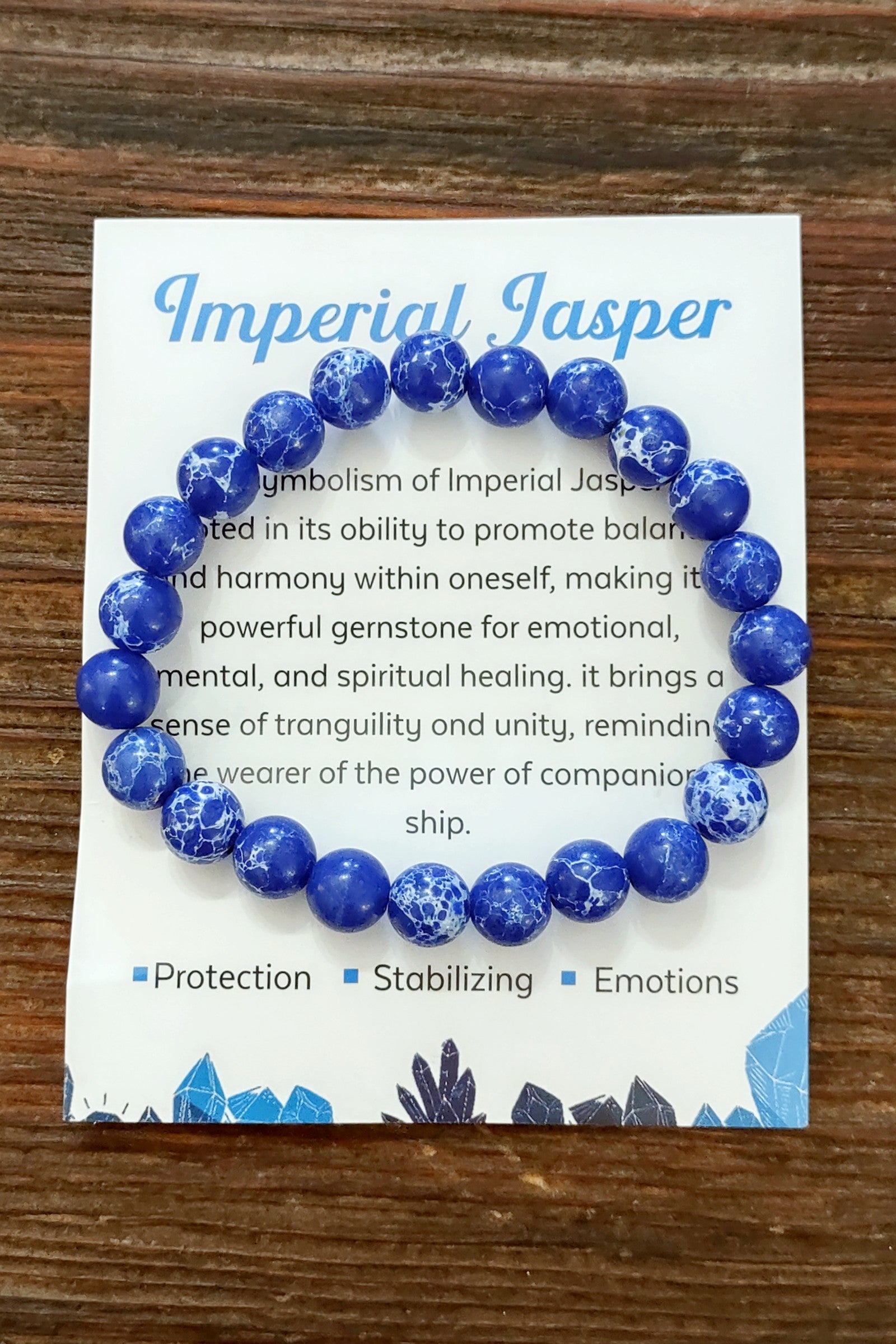 Blue beaded bracelet on a card with text about Imperial Jasper on a wooden surface