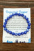 Blue beaded bracelet on a card with text about Imperial Jasper on a wooden surface