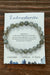 Labradorite bracelet on a card with descriptive text on a wooden surface