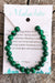 Green beaded bracelet on a card with text about malachite on a wooden surface