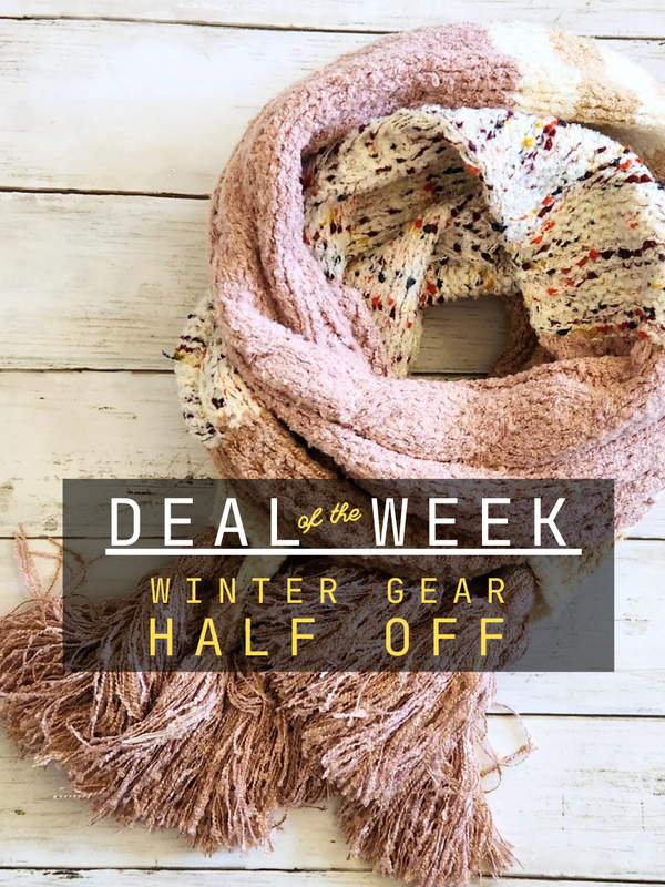 Scarf draped over a cake with promotional text 'Deal of the Week: Winter Gear Half Off' on a wooden surface.