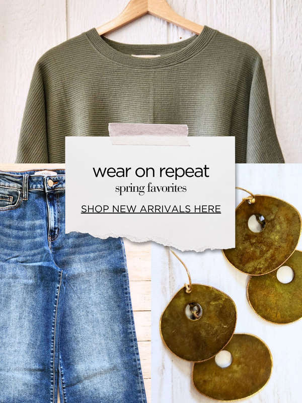 Green sweatshirt on a hanger with jeans and decorative items on a white surface, featuring text about spring favorites and new arrivals.